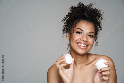 Image of shirtless woman smiling and posing with face cream