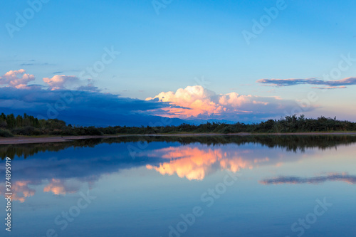 Fototapeta Naklejka Na Ścianę i Meble -  Beautiful sunset by the lake. Bright clouds are reflected in the water. Kyrgyzstan.