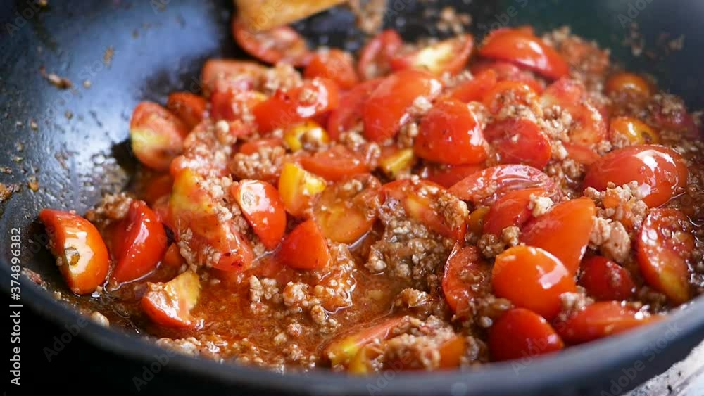 Close-up of cooking tomatoes and pork chops in red curry paste in pan (Nam Prik Ong). Famous food in the north of Thailand. Close-up of cooking tomatoes and pork chops in red curry paste in pan (Nam Prik Ong). Famous food in the north of Thailand.