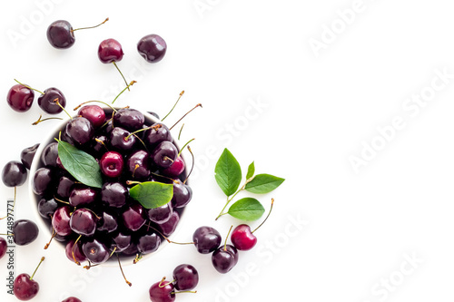 Plate of ripe red cherries with leaves, top view