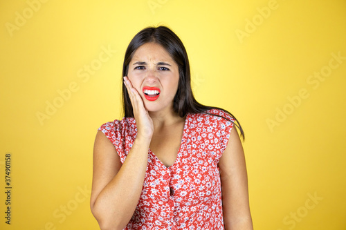 Young beautiful woman over isolated yellow background ouching mouth with hand with painful expression because of toothache or dental illness on teeth