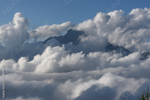 Rocky mountain peak of the Alps, emerging from the clouds, seen above the clouds, from within the cloud. Above all, the sky is blue and the clouds are below the peaks and the photographer, photo taken © Javier Peribáñez