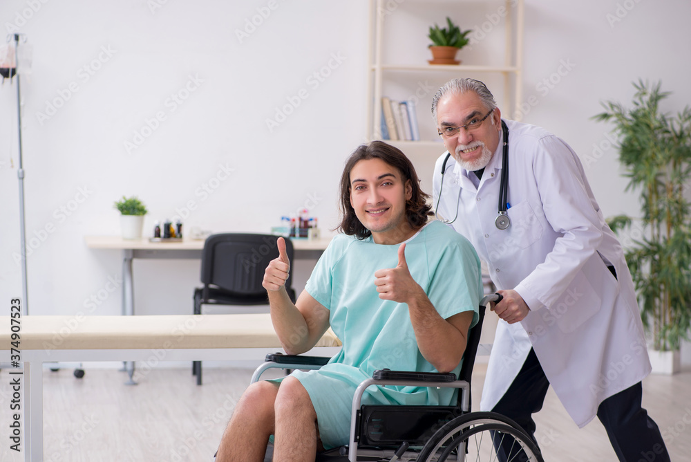 Young male patient in wheel-chair and experienced doctor traumatologist Young male patient in wheel-chair and experienced doctor traumatologist