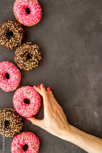 Hand holding donut with icing and sprinkles. Flat lay, top view