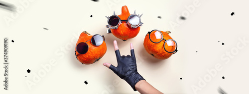 Three orange rocker pumpkins with glasses and a mustache on a light background. Halloween concept