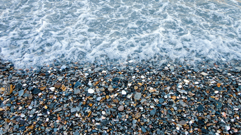 Stony beach on a sunny day. Background of different pebbles from above on the beach Stony beach on a sunny day. Background of different pebbles from above on the beach