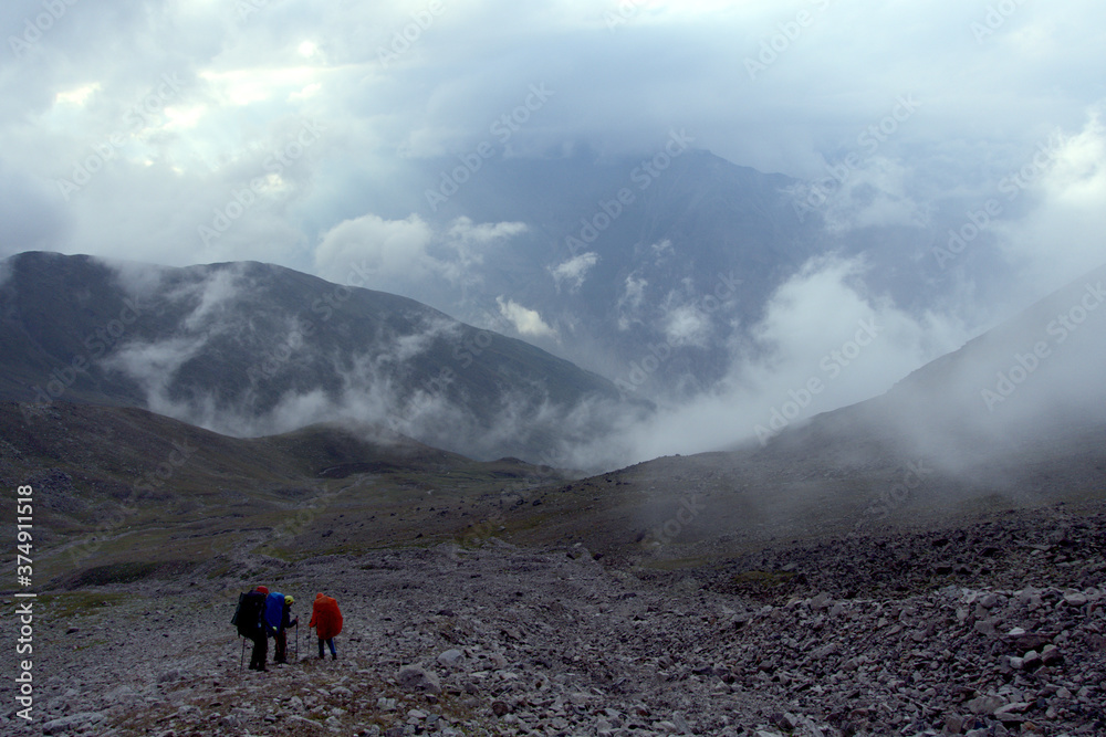 Tourists hike through the valley. View from the Kashtan Pass, Caucasus, Russia. Height 3513 meters above sea level.