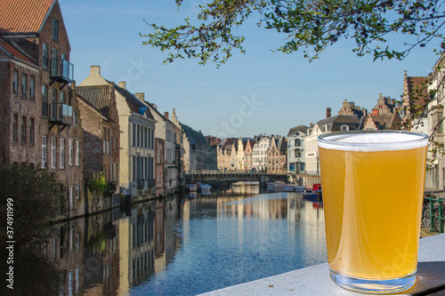 Glass of light beer against canal and historic buildings in Ghent, Belgium © Maria Vonotna