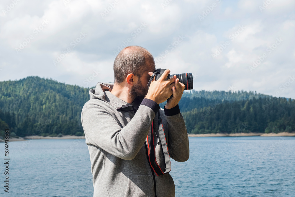 Adult man in hoodie walking around lake with DSLR camera and shooting, beautiful summer day, half body portrait, landscape photography concept
Adult man in hoodie walking around lake with DSLR camera and shooting, beautiful summer day, half body portrait, landscape photography concept