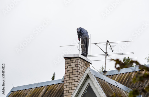 Konstfotografi Chimney sweeper clears ash and soot from chimneys on cloudy autumn day