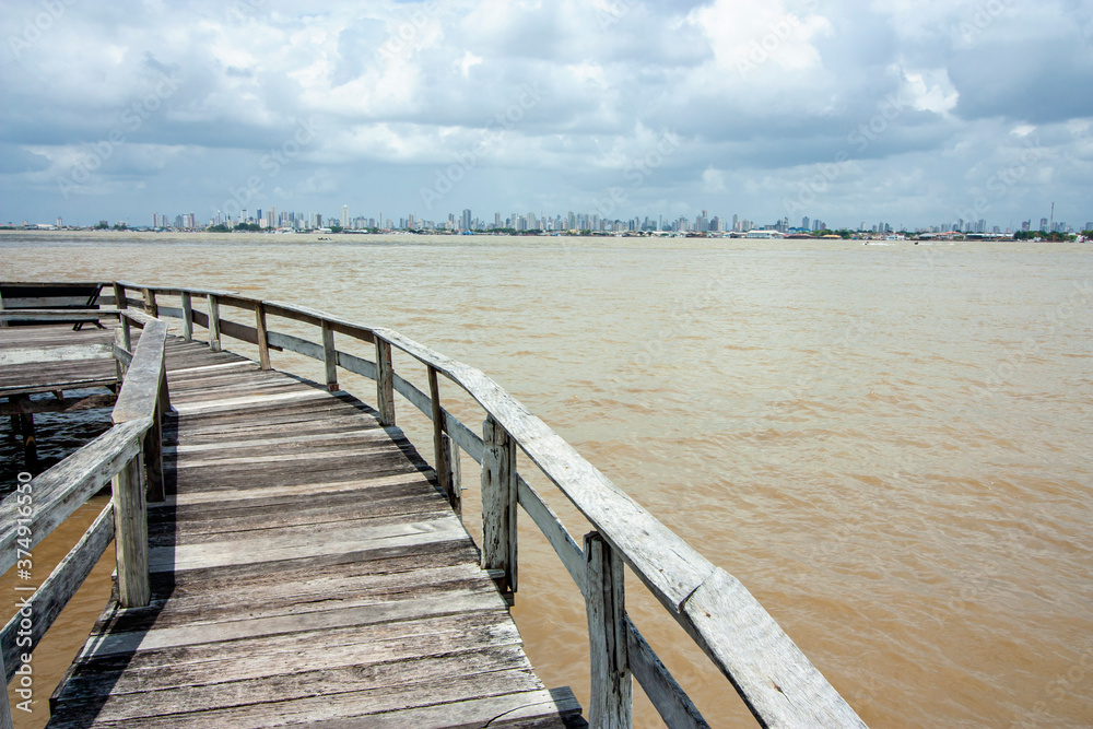 Trapiche de madeira na beira do rio na margem do rio Guajará, com Belém do Pará na linha do horizonte.