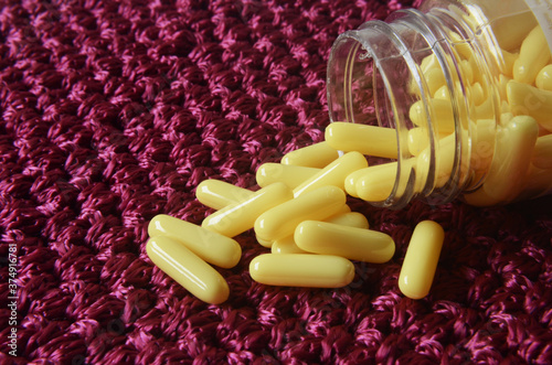 pill spilling out of pill bottle, yellow and red pills photo