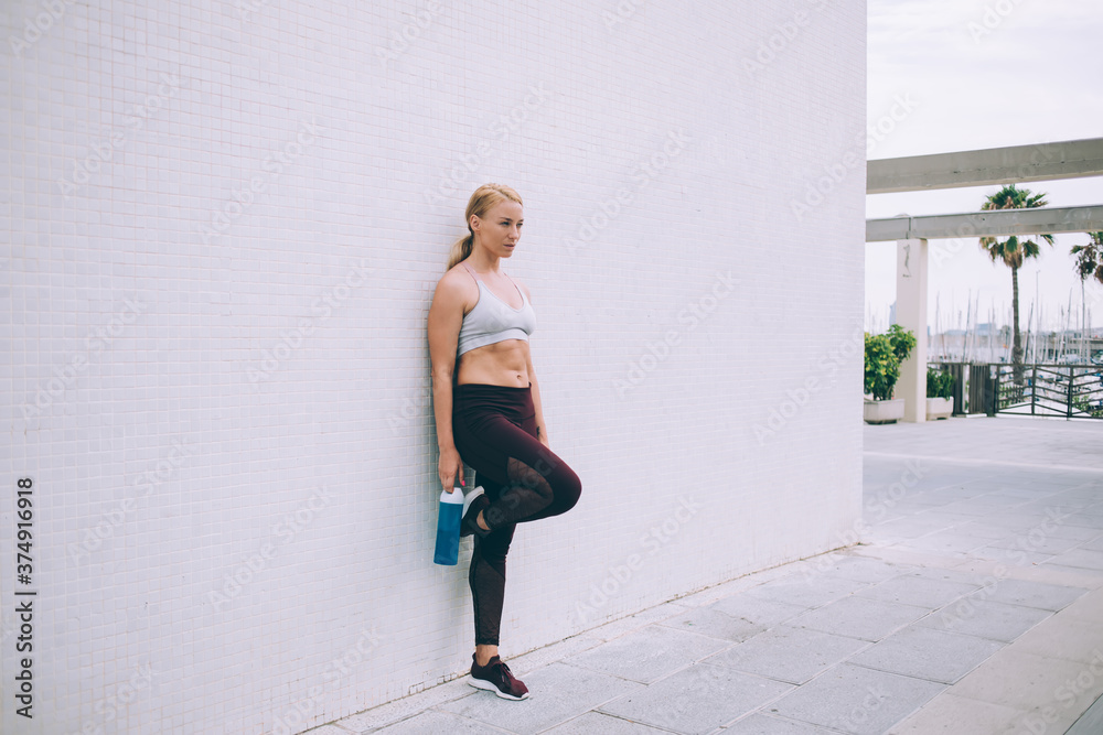 Female athlete leaned with one leg on wall Female athlete leaned with one leg on wall