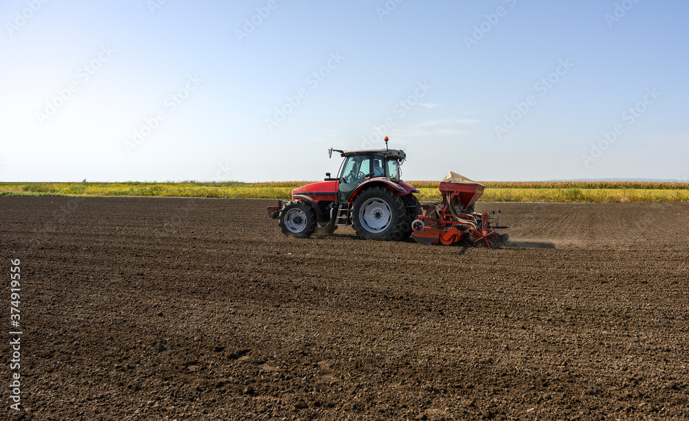Farmer with tractor seeding crops at field Farmer with tractor seeding crops at field