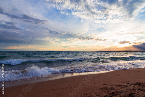 Beautiful sunset by the lake. Bright clouds are reflected in the water. Kyrgyzstan.