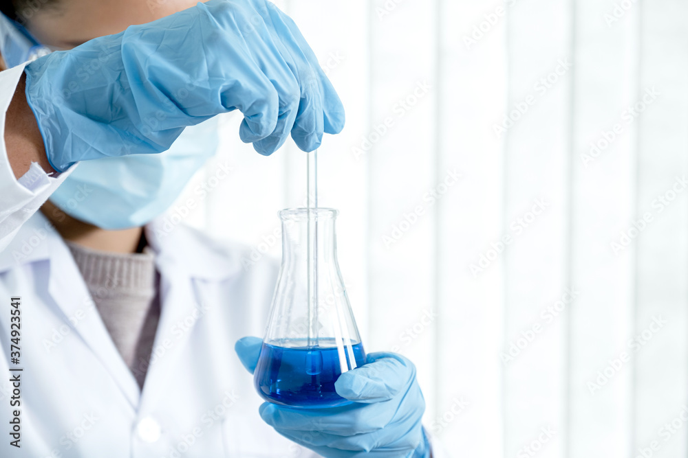 Scientists hold a glass tube filled with blue chemical liquid for research and analysis in a laboratory Scientists hold a glass tube filled with blue chemical liquid for research and analysis in a laboratory