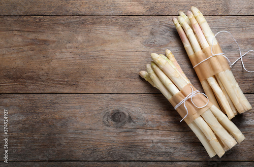 Bunches of fresh white asparagus on wooden table, flat lay. Space for text