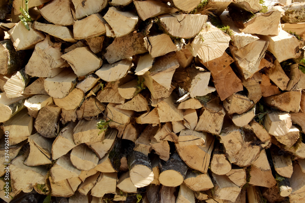 A stack of dry firewood. Preparation of firewood for the winter. Background from dry, chopped firewood. A stack of dry firewood. Preparation of firewood for the winter. Background from dry, chopped firewood.