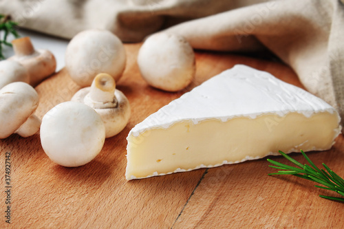 Brie cheese on a wooden board with mushrooms and rosemary