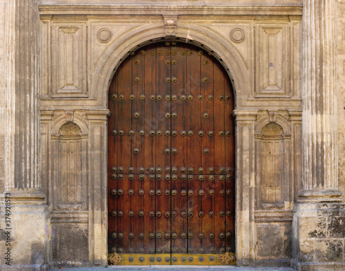 ancient door in the old town with a wooden gate, stone semicircular arch with ornaments in the facade around the entrance of a medieval palace or a church