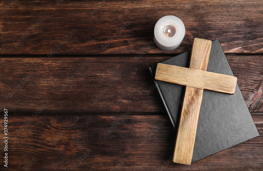 Cross, Bible and burning candle on wooden background, flat lay with space for text. Christian religion