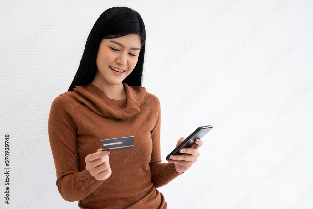Happy Asian woman holding card credit and smartphone for mobile banking on the internet. Concept of new lifestyle and financing technology. Happy Asian woman holding card credit and smartphone for mobile banking on the internet. Concept of new lifestyle and financing technology.