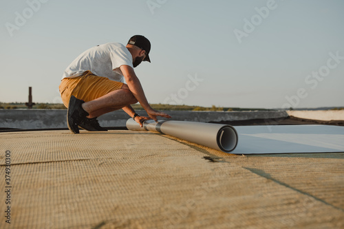 Worker applies pvc membrane roller on roof