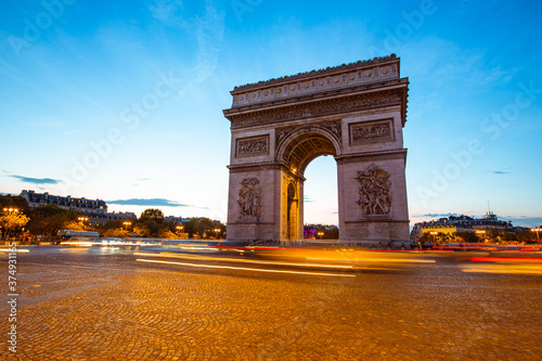 The night view of triumphal arch and traffic in Paris, France.