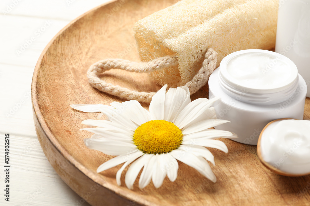 Cosmetic products, chamomile and loofah on wooden plate, closeup Cosmetic products, chamomile and loofah on wooden plate, closeup