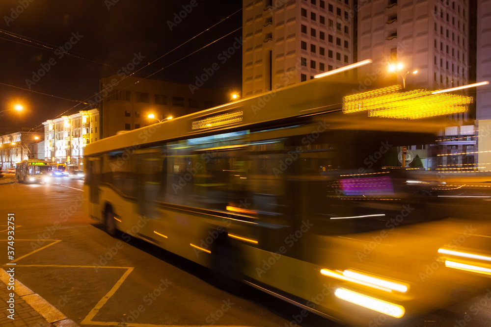 The motion of a blurred bus along the avenue in the evening The motion of a blurred bus along the avenue in the evening