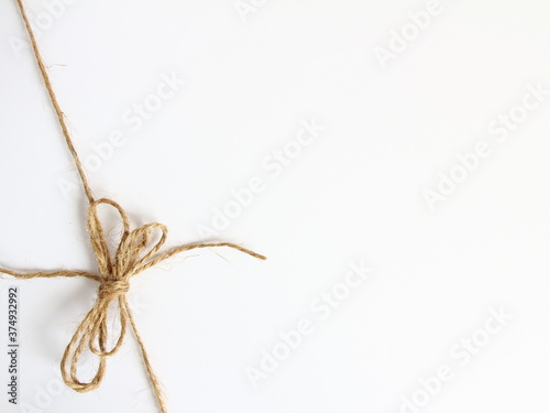 Kokarda z naturalnego sznurka jutowego zawiązana w lewym dolnym narożniku - dekoracja do pakowania wiązania prezentów
