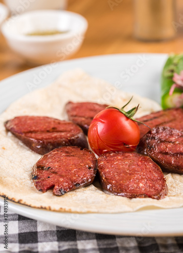Sliced Turkish sausage on ​​white plate cooked on the grill.