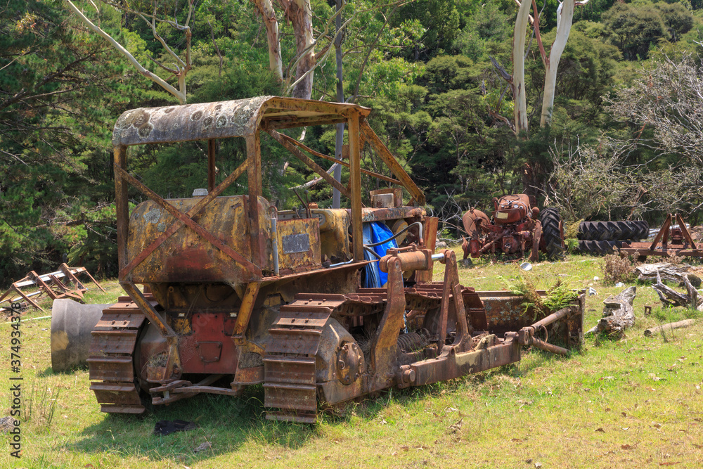Old, rusty bulldozer, abandoned in a field with other machinery Old, rusty bulldozer, abandoned in a field with other machinery