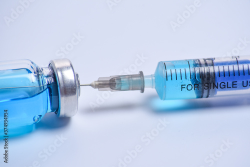 Medical syringe and blue vial vaccine on white background with selective focus and crop fragment