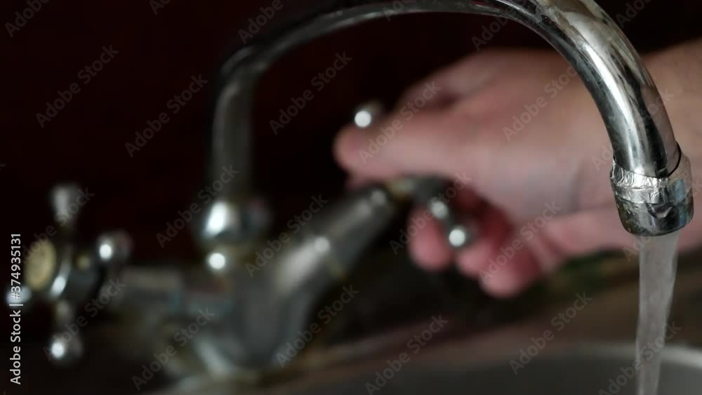 Kitchen faucet and sink in the kitchen. Male water turns the knob and opens the stream of water. Then he closes the tap. Old faucet in the kitchen. Metal Chrome Plated Water Mixer Kitchen faucet and sink in the kitchen. Male water turns the knob and opens the stream of water. Then he closes the tap. Old faucet in the kitchen. Metal Chrome Plated Water Mixer