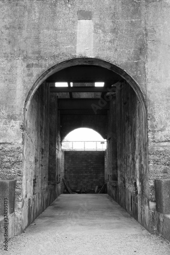 An archway in an old ruined stone building. Black and white with strong texture