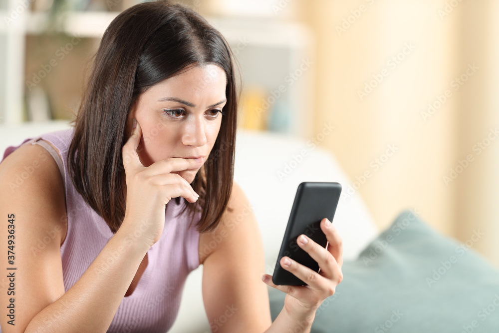 Pensive woman checking smart phone content at home Pensive woman checking smart phone content at home