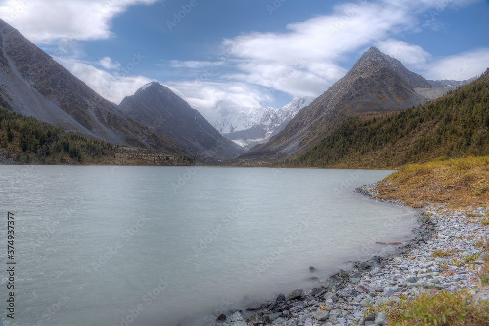 A beautiful lake in a mountain valley. Soft focus. Wide angle shot. High mountains, glacier, blue sky.