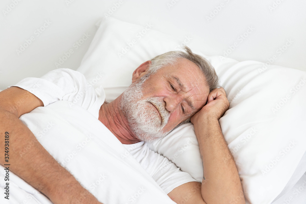 Worried senior retirement man lying awake in his bed Worried senior retirement man lying awake in his bed