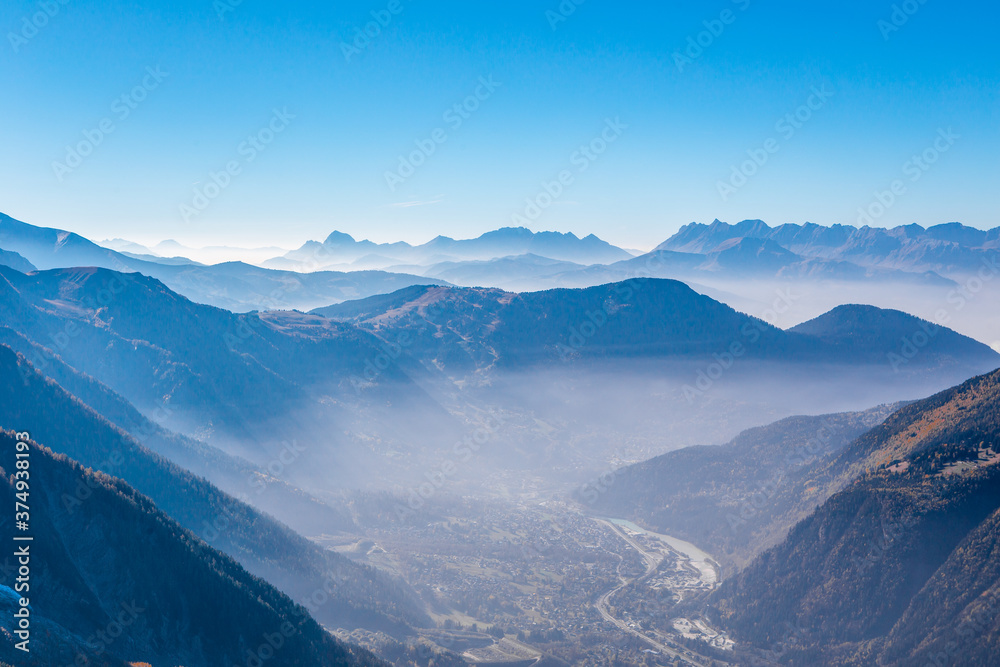 The Chamonix valley in the Alps, France, on a sunny day, with a thin fog covered.
