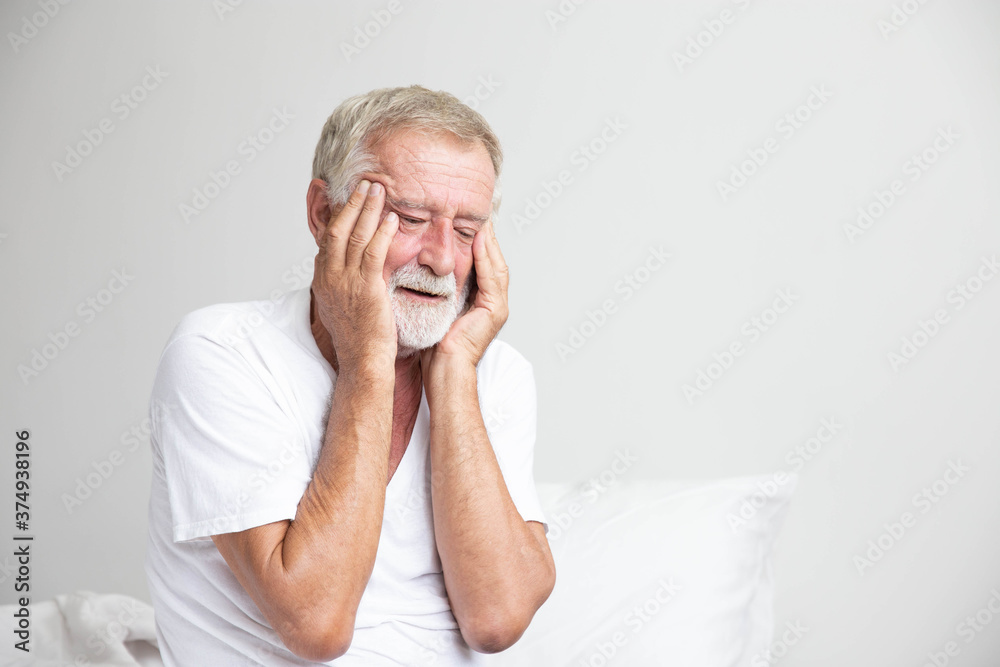 Portrait of a senior retirement man sitting and thinking alone on bed in his home Portrait of a senior retirement man sitting and thinking alone on bed in his home