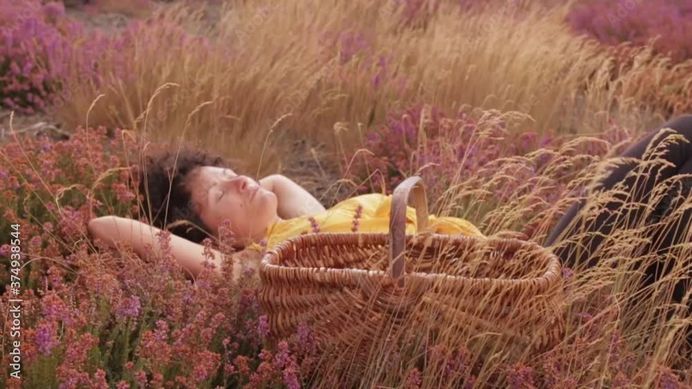 une jeune femme naturelle fait une sieste dans un champ fleurie automnale.