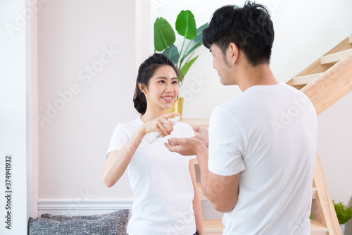 Asian woman looking at man and helping him use sanitizer alcohol gel to washing hand for prevent viruses and bacteria.