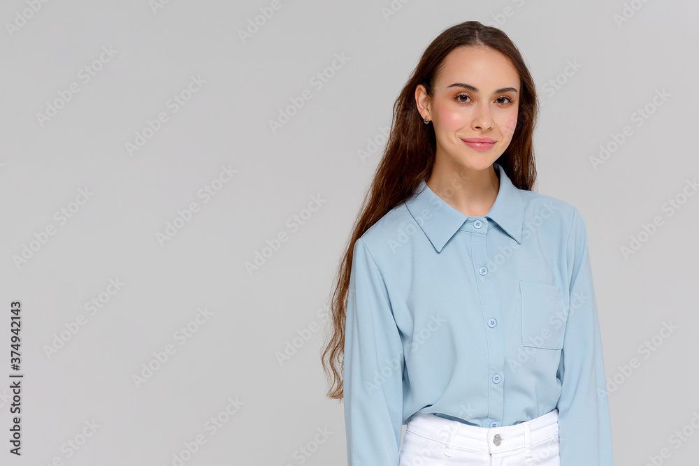 Close up portrait of smiling young woman in blue shirt looking at camera, isolated on gray background Close up portrait of smiling young woman in blue shirt looking at camera, isolated on gray background