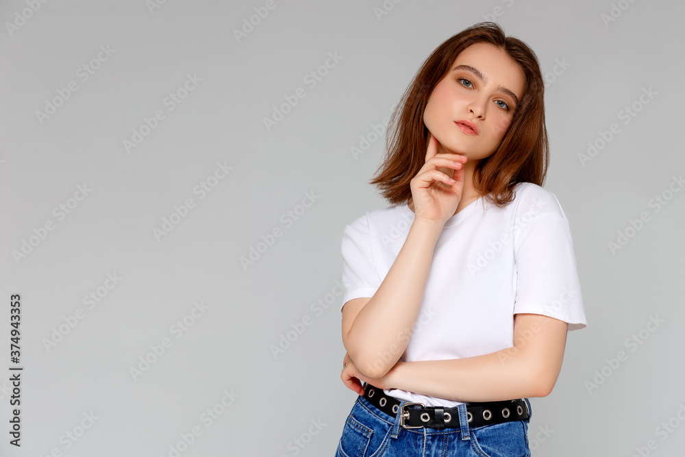 Hmm, nice plan. Portrait of thoughtful attractive and funny young european female with messy bun in t-shirt holding hand on chin looking at upper left corner as thinking having idea and liking it Hmm, nice plan. Portrait of thoughtful attractive and funny young european female with messy bun in t-shirt holding hand on chin looking at upper left corner as thinking having idea and liking it
