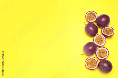 Fresh ripe passion fruits (maracuyas) on yellow background, flat lay. Space for text