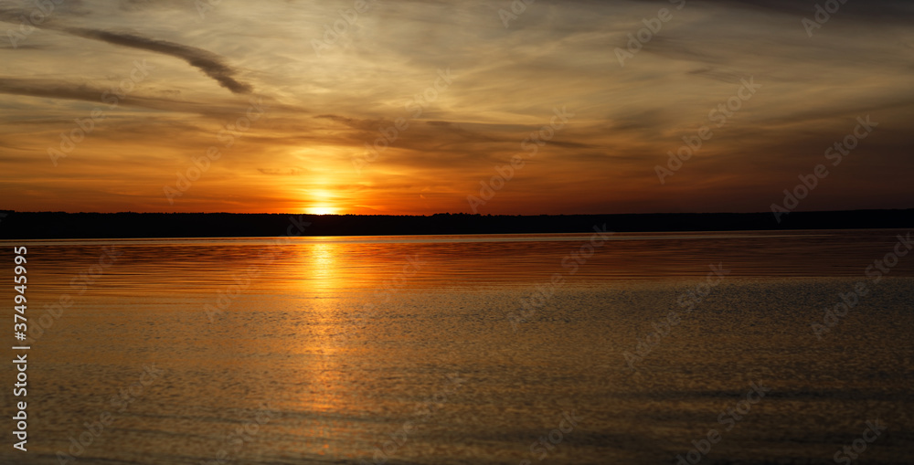 Golden sunset on the sea shore. View from the water to the shore.