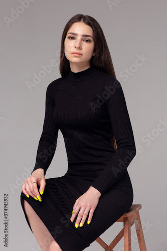 Beautiful woman standing in a black dress over gray background