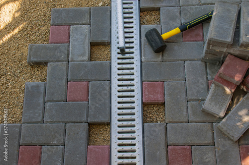 Installation of light metal grating and gutters for drainage of rainwater and paving slabs. Selective focus.