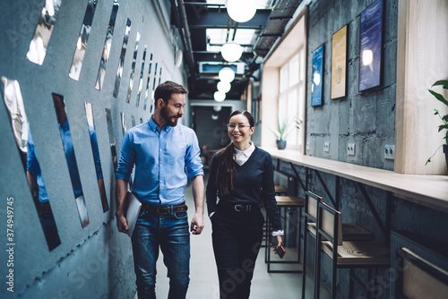 Man with laptop accompanying smiling woman in glasses